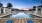 a pool with a deck and chairs by it and buildings in the background