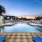 a pool with a deck and chairs by it and buildings in the background