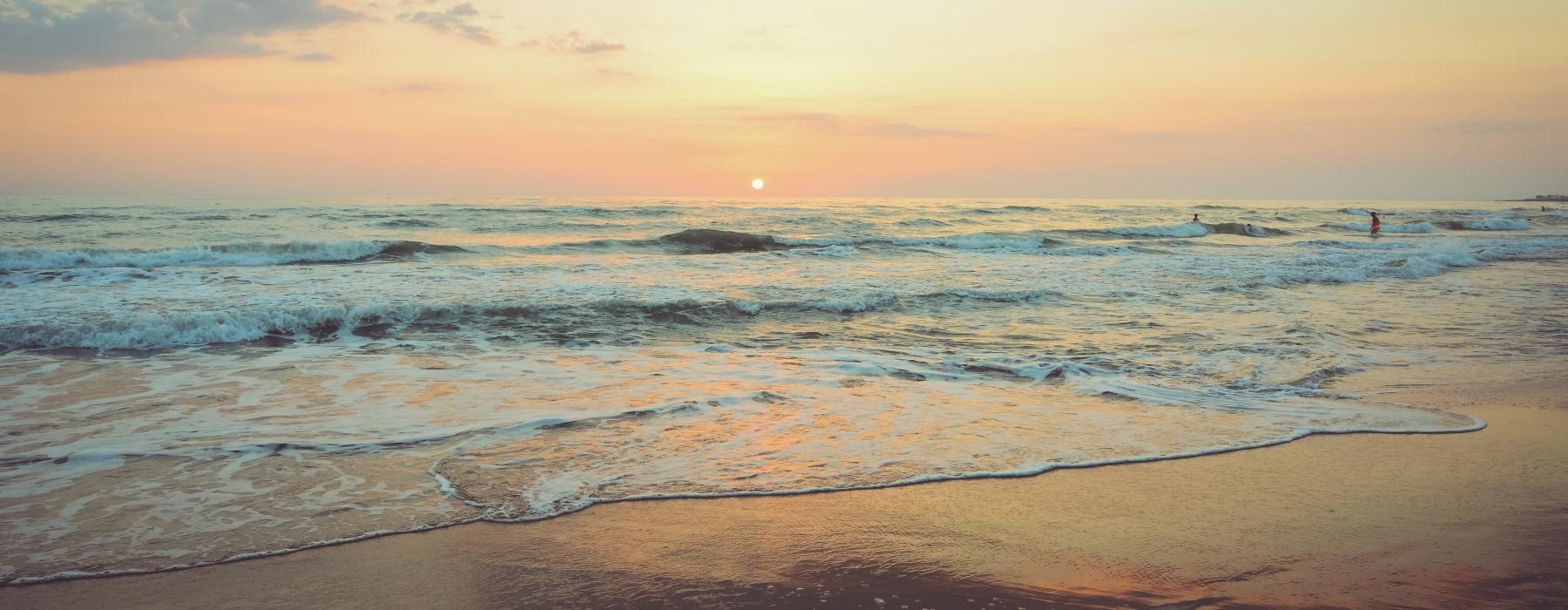 a beach with waves and a sunset